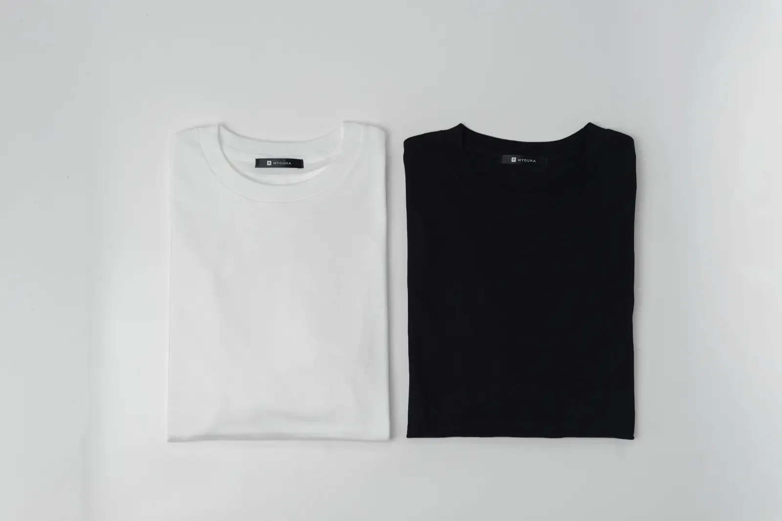 たたまれた白と黒のMYOHA Tシャツ。物販事業で取り扱う綿100%のコンディショニングウェア